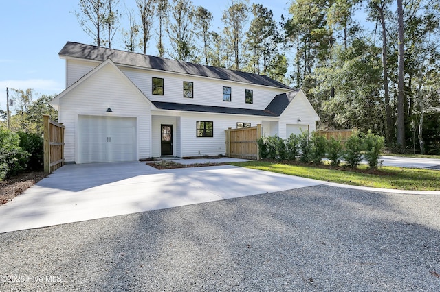 view of front facade with a garage, driveway, and fence