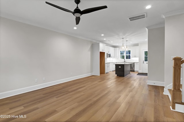 unfurnished living room with ornamental molding, baseboards, visible vents, and light wood finished floors