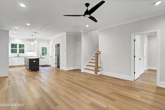 unfurnished living room featuring light wood finished floors, stairs, baseboards, and crown molding