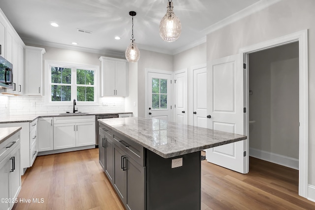 kitchen with visible vents, white cabinets, a kitchen island, light stone counters, and hanging light fixtures