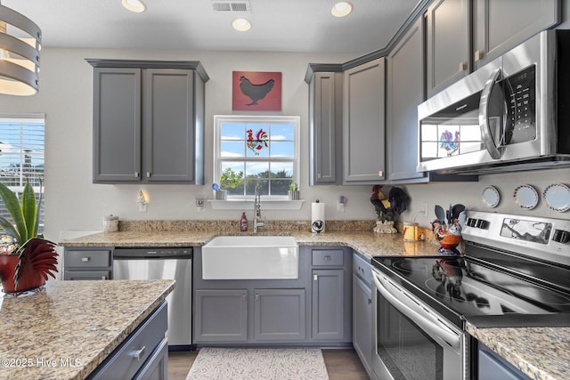 kitchen with stainless steel appliances, gray cabinets, and a sink