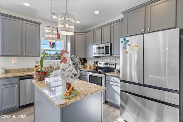 kitchen with hanging light fixtures, a kitchen island, gray cabinets, and stainless steel appliances