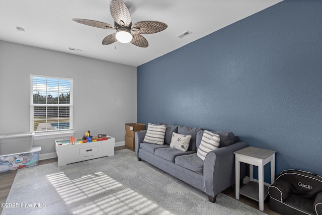 living area featuring baseboards, visible vents, and ceiling fan