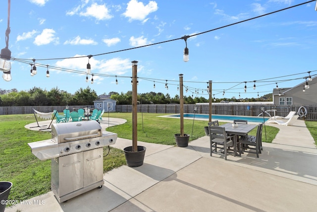 view of patio with a fenced in pool, area for grilling, a shed, a fenced backyard, and an outdoor structure