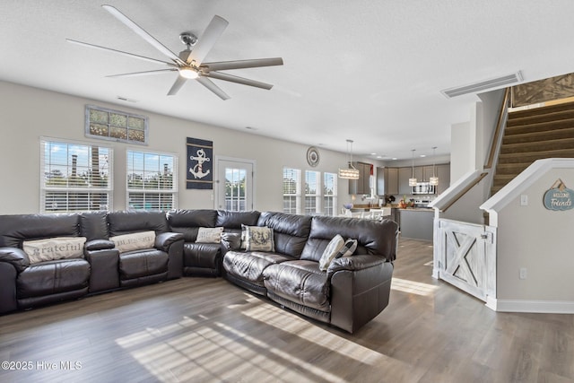 living room with stairs, dark wood-type flooring, a textured ceiling, and visible vents