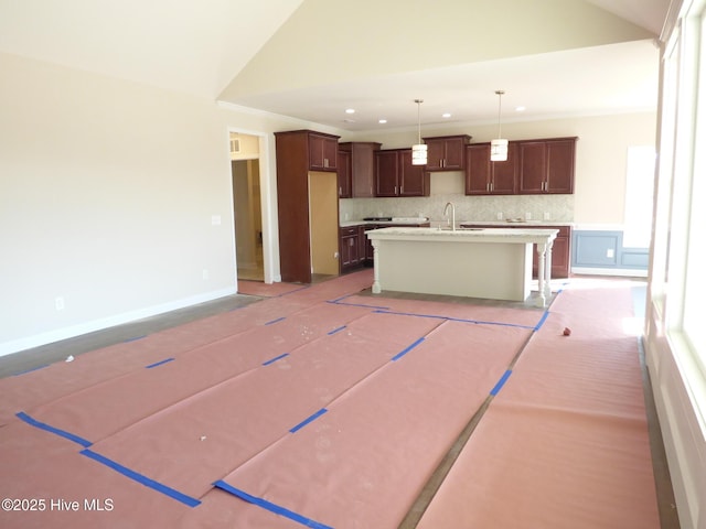 kitchen featuring open floor plan, a sink, hanging light fixtures, and an island with sink