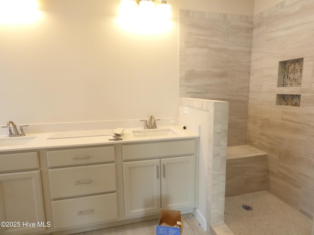 bathroom with a sink, a tile shower, and double vanity