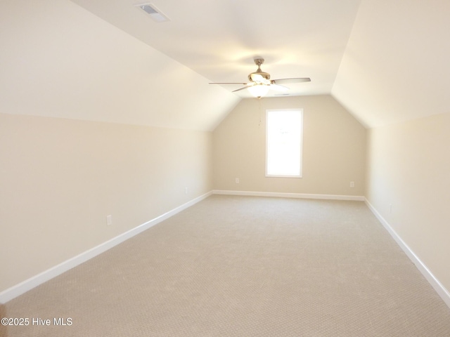 additional living space featuring visible vents, baseboards, a ceiling fan, light colored carpet, and vaulted ceiling