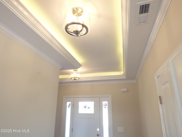 entrance foyer with ornamental molding, a tray ceiling, and visible vents