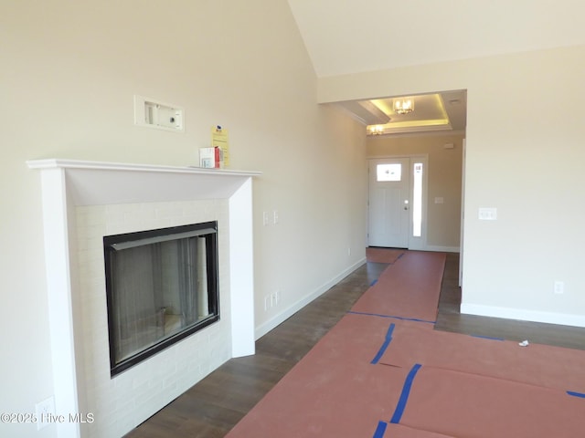 interior space with lofted ceiling, dark wood-type flooring, a fireplace, and baseboards