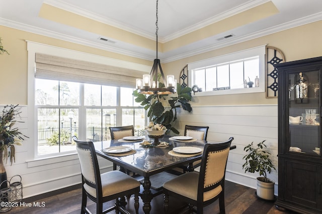 dining room with dark wood-style flooring, a raised ceiling, and visible vents