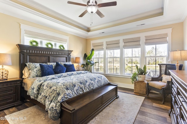 bedroom featuring dark wood finished floors, a raised ceiling, visible vents, and crown molding