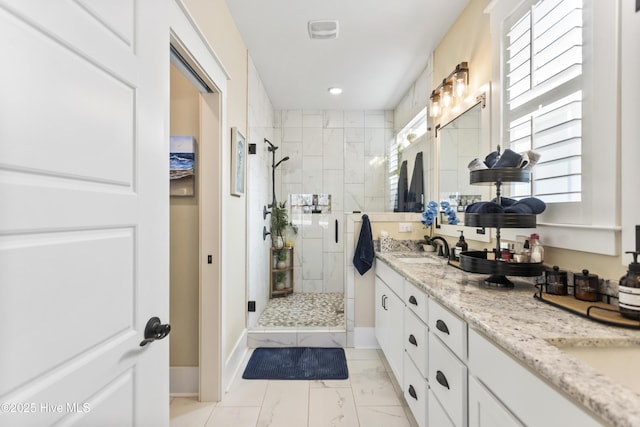 full bathroom with double vanity, marble finish floor, a shower stall, and a sink