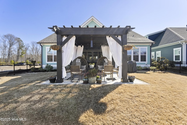 back of house featuring a shingled roof, a lawn, a patio area, and fence