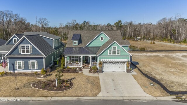 craftsman-style house featuring a garage, concrete driveway, metal roof, a standing seam roof, and a porch