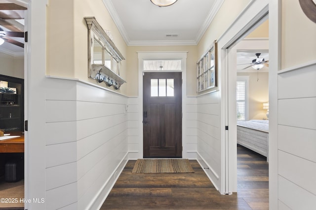 entryway with dark wood-type flooring, visible vents, ornamental molding, and ceiling fan