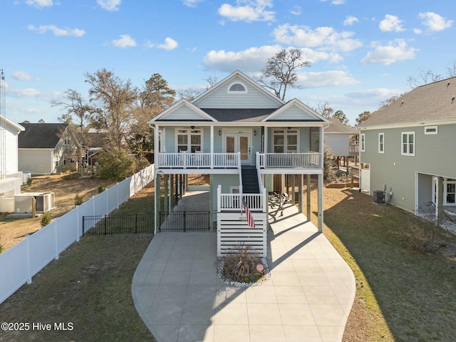 coastal inspired home featuring driveway, ceiling fan, a porch, a carport, and a front yard