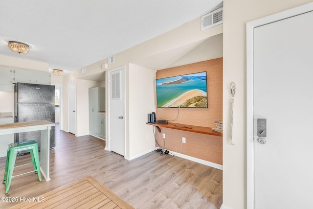 kitchen featuring freestanding refrigerator, visible vents, and light wood-style floors