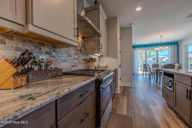 kitchen with decorative backsplash, light stone counters, dark wood-style flooring, stainless steel appliances, and wall chimney range hood