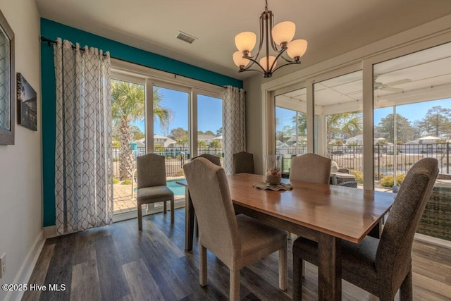 dining space with baseboards, a notable chandelier, visible vents, and wood finished floors