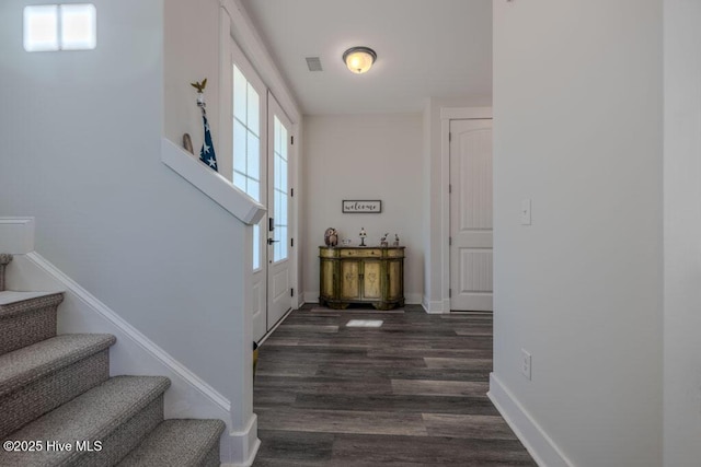 entryway with dark wood-type flooring, visible vents, baseboards, and stairs