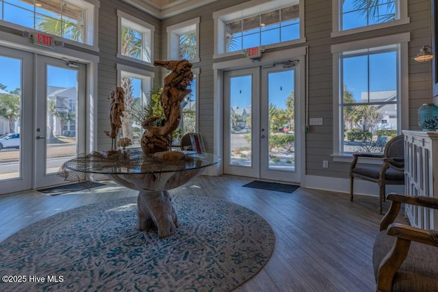 interior space with french doors, wood finished floors, a towering ceiling, and wooden walls