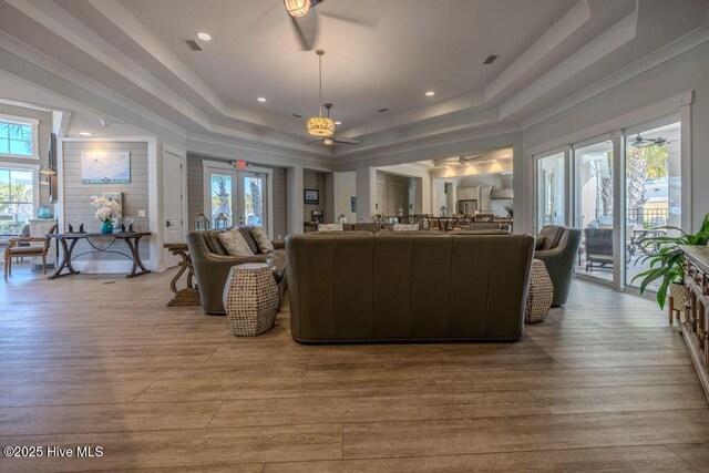 living room featuring light wood-style floors, a raised ceiling, visible vents, and french doors