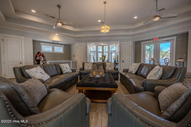 living room with a tray ceiling, french doors, recessed lighting, visible vents, and light wood-type flooring