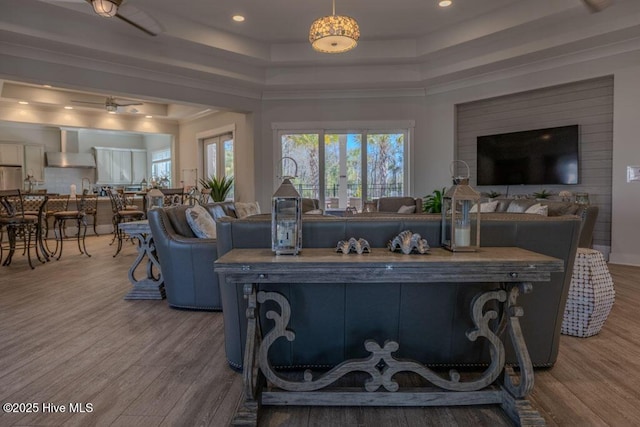 living room with a tray ceiling, wood finished floors, and recessed lighting