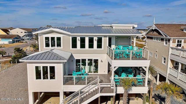 rear view of house featuring a standing seam roof, metal roof, stairway, and a balcony