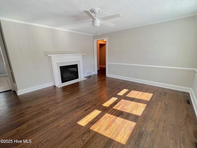 unfurnished living room with dark wood-type flooring, ornamental molding, a fireplace with flush hearth, ceiling fan, and a textured ceiling