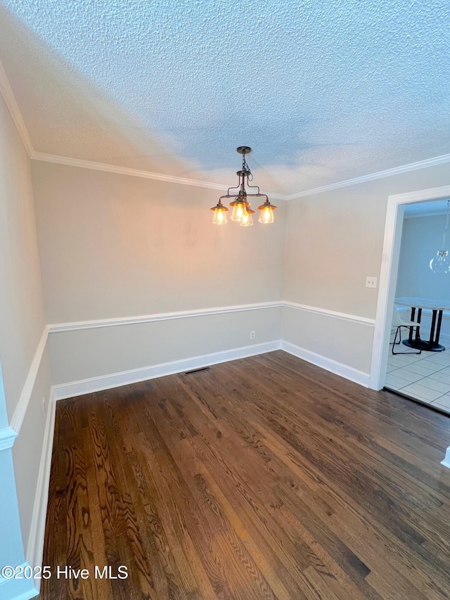 unfurnished room featuring a textured ceiling, a chandelier, dark wood-type flooring, and ornamental molding