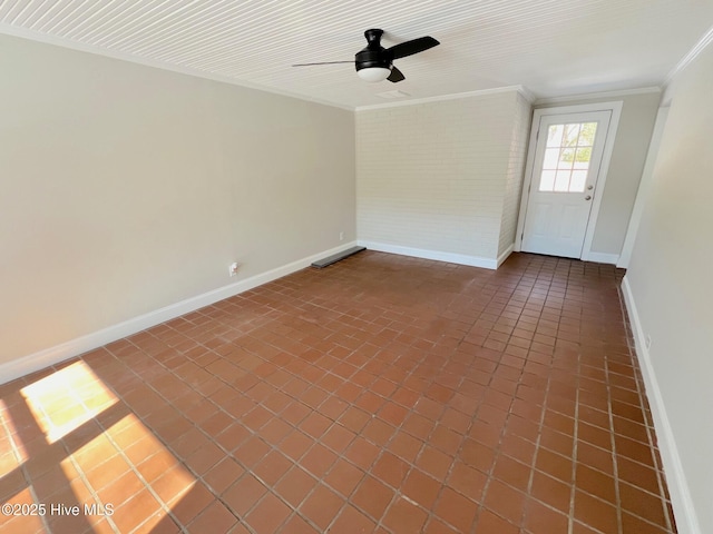 spare room with baseboards, crown molding, dark tile patterned floors, and brick wall