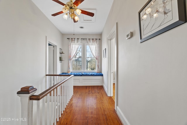 hallway with visible vents, wood finished floors, an upstairs landing, and baseboards