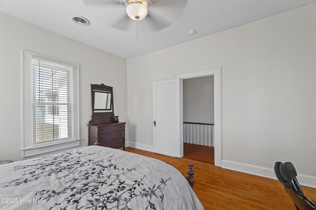 bedroom featuring a ceiling fan, baseboards, visible vents, and wood finished floors