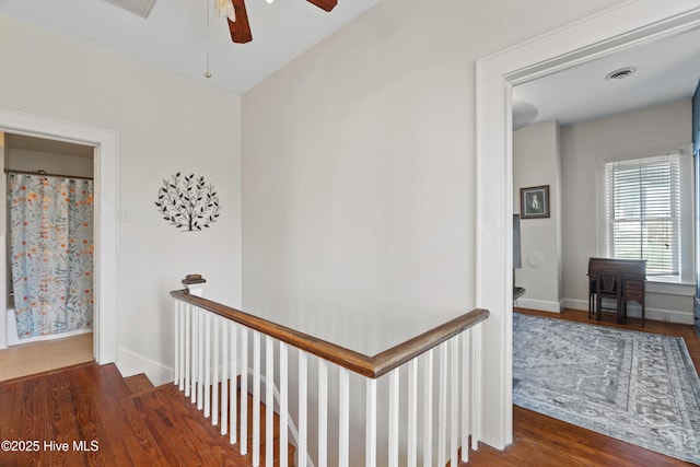 corridor featuring baseboards, visible vents, an upstairs landing, and wood finished floors