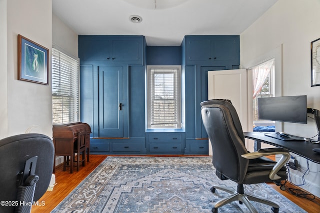 office space with a wealth of natural light, visible vents, and wood finished floors