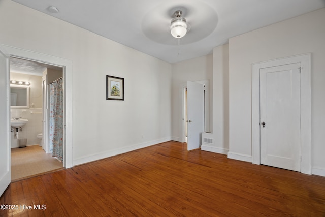 unfurnished bedroom with baseboards, visible vents, hardwood / wood-style floors, and ensuite bathroom