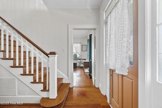 foyer with stairs, wood finished floors, visible vents, and crown molding