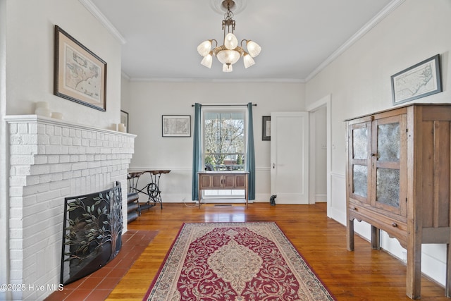 entryway with a chandelier, a brick fireplace, crown molding, and wood finished floors