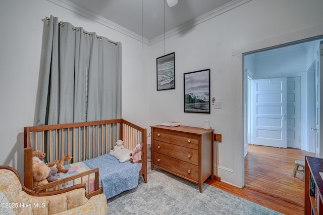 bedroom with baseboards, wood finished floors, and crown molding