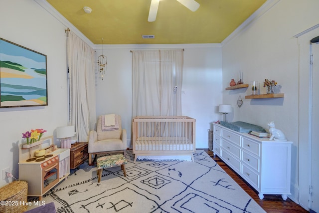 bedroom with ceiling fan, dark wood-style flooring, visible vents, and crown molding