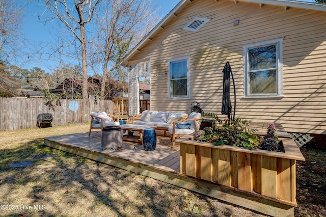 back of property with a deck, fence, and an outdoor living space