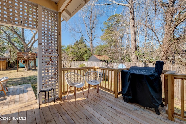 wooden terrace featuring a fenced backyard, a playground, and grilling area