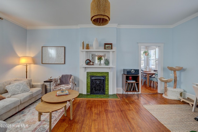 living area with baseboards, a fireplace with flush hearth, ornamental molding, and wood finished floors