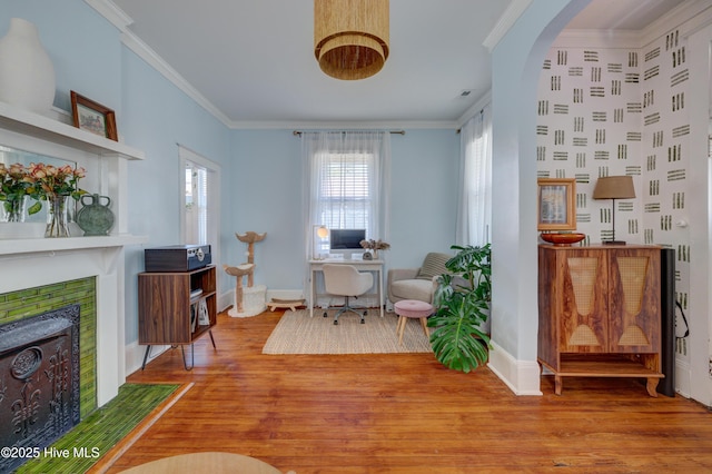 living area featuring light wood finished floors, baseboards, ornamental molding, and a tile fireplace