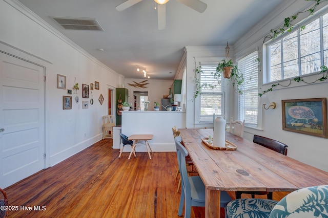 dining space with visible vents, ornamental molding, a ceiling fan, wood finished floors, and baseboards