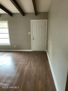 spare room with dark wood-style floors, beam ceiling, and baseboards