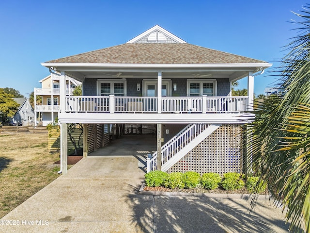 212 Florida Ave, Carolina Beach, NC 28428 - coastal inspired home featuring covered porch, a shingled roof, concrete driveway, stairway, and a carport