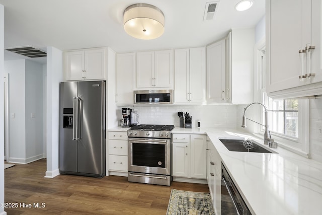 212 Florida Ave, Carolina Beach, NC 28428 - kitchen featuring stainless steel appliances, a sink, white cabinets, decorative backsplash, and recessed lighting